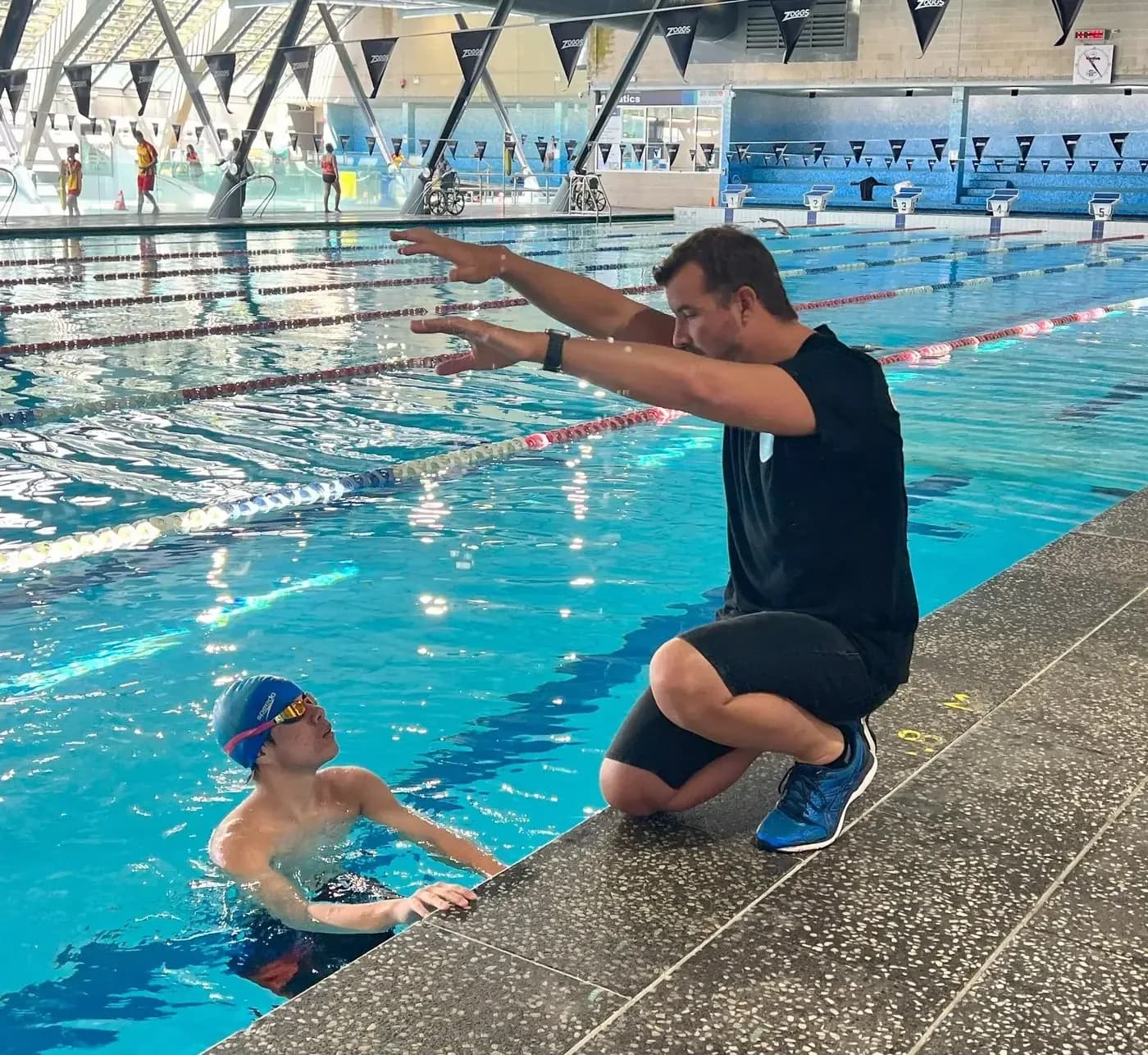 Jason Cram showing a swimmer a stroke position at the pool edge
